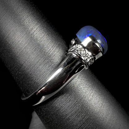 Side view of a platinum black opal and diamond ring.  The opal has blue color play.