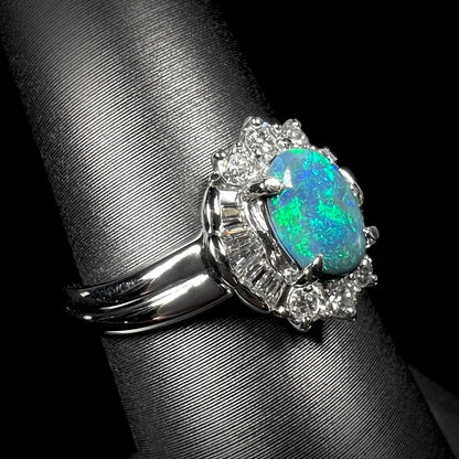 Macro angled view of platinum black opal engagement ring showcasing diamond halo and green opal color.