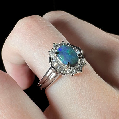 Macro closeup of platinum black opal engagement ring, showcasing diamond halo with baguette diamonds and blue color play in the opal.