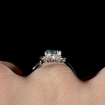 Platinum black opal engagement ring displayed on a finger against a black background, showcasing the gallery view and contemporary setting.