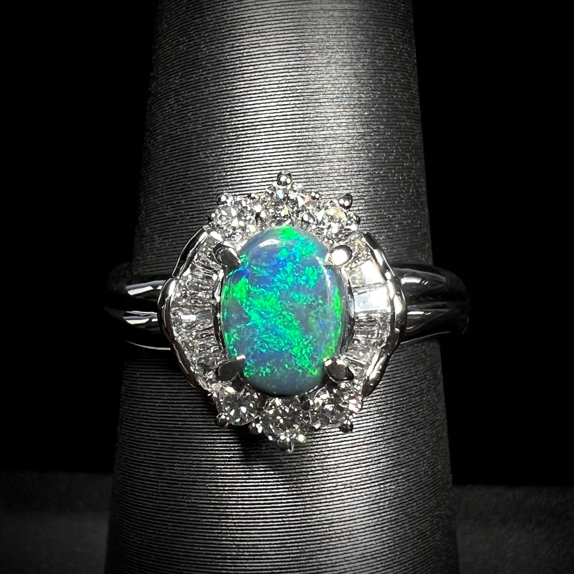 Straight-on macro shot of platinm black opal engagement ring showcasing green flashes of color.