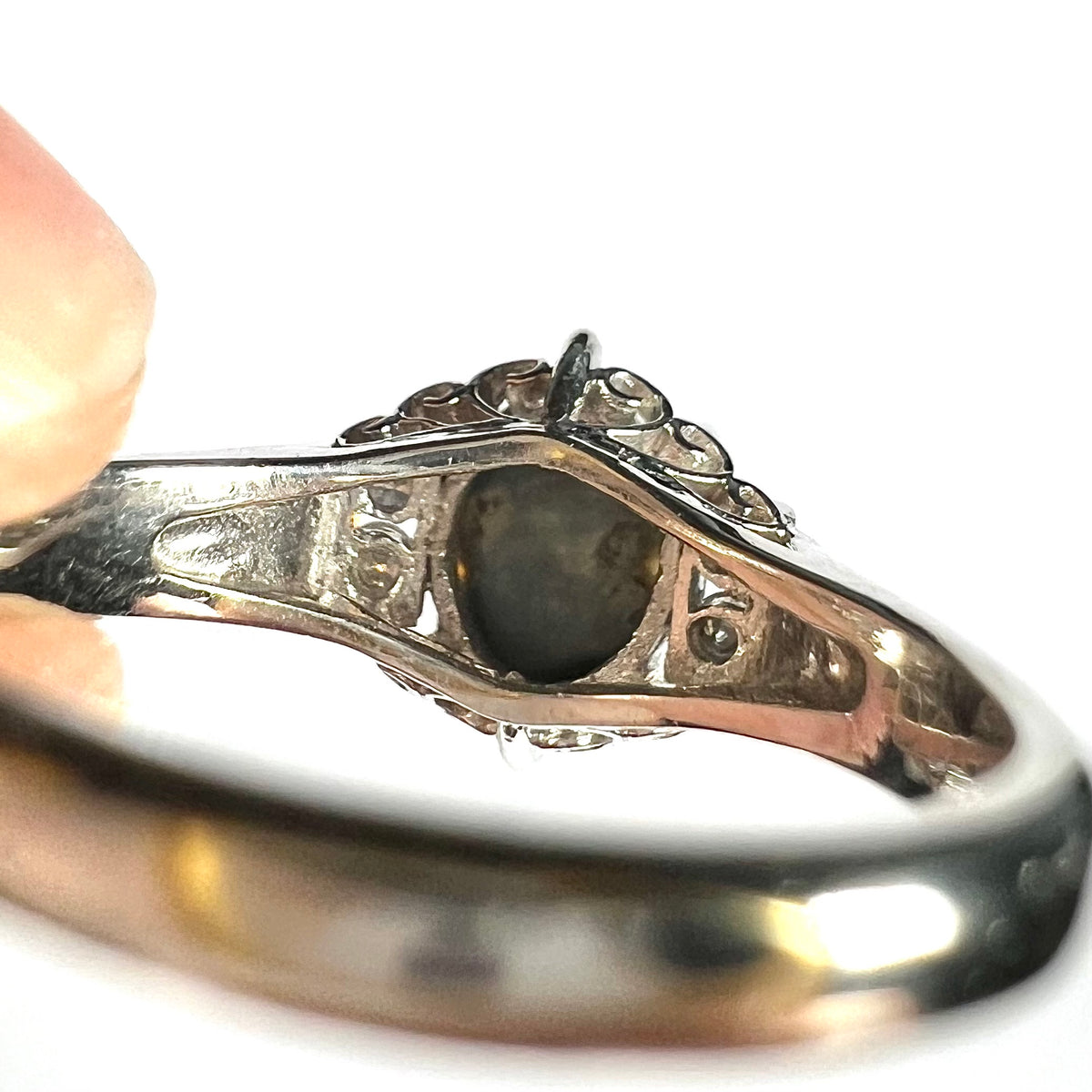 Underside view of a platinum ring set with natural Australian black opal showing its irregular natural gray potch and matrix backing.