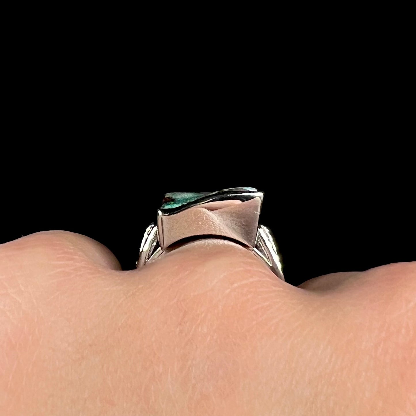 Close-up gallery view of a platinum boulder opal ring worn on a hand, shown against a black background.