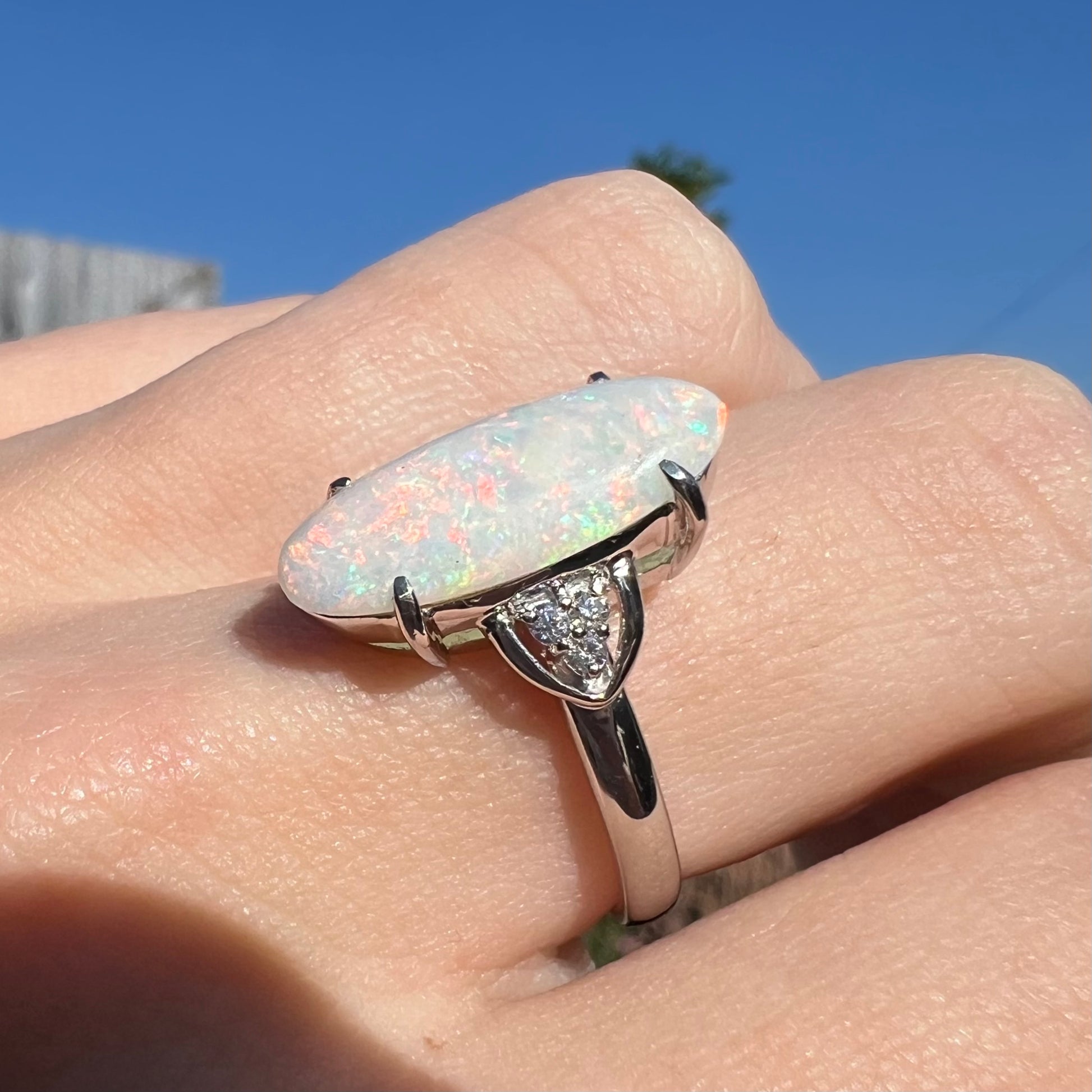 A Coober Pedy white opal platinum ring set with diamond accents.  The opal plays soft pink colors.