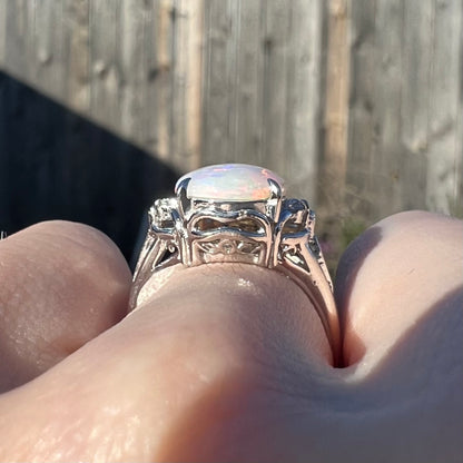 The gallery view of a platinum Coober Pedy opal ring while worn on a hand in the sunlight.