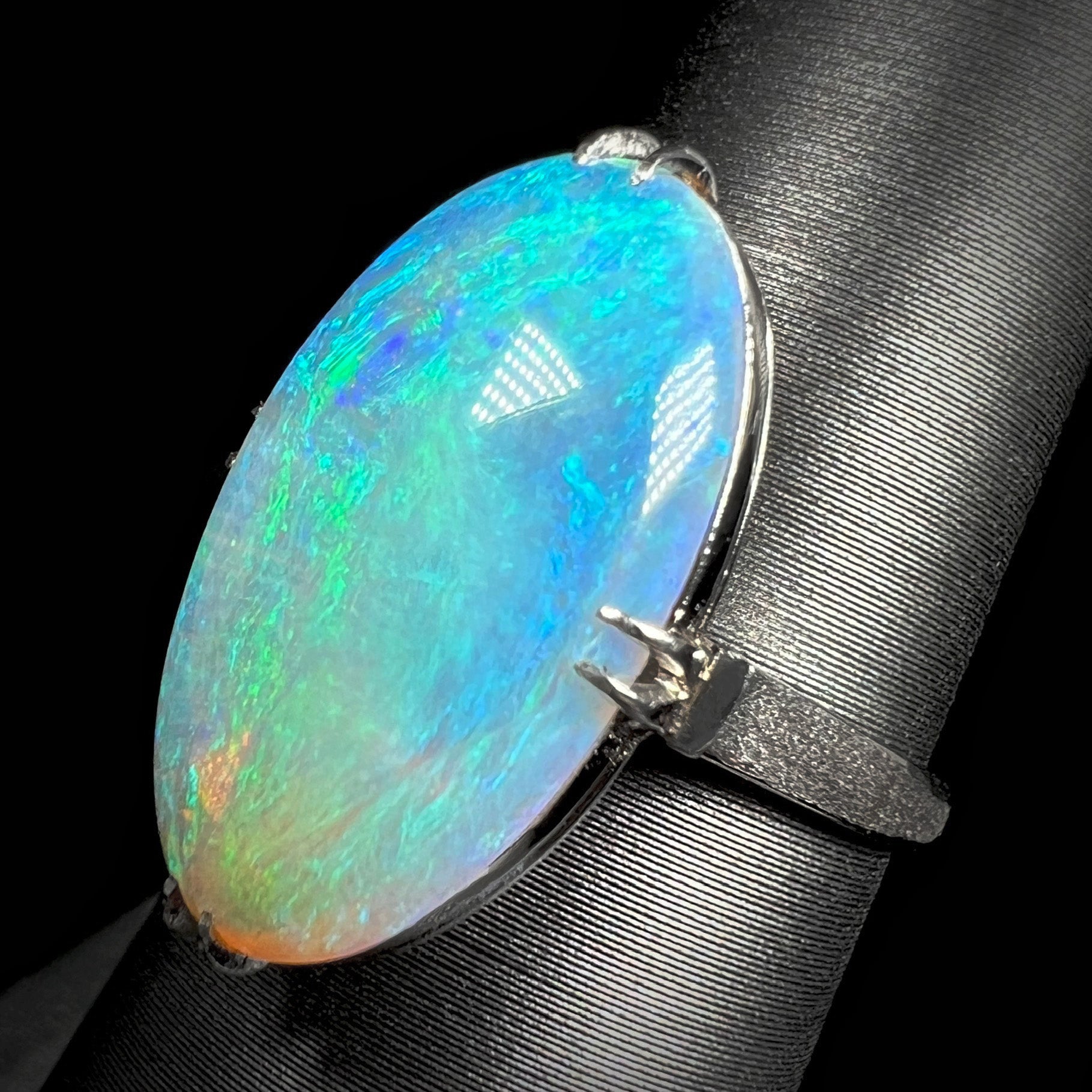 Angled macro view of a platinum crystal opal ring.  The opal has green-blue color play.