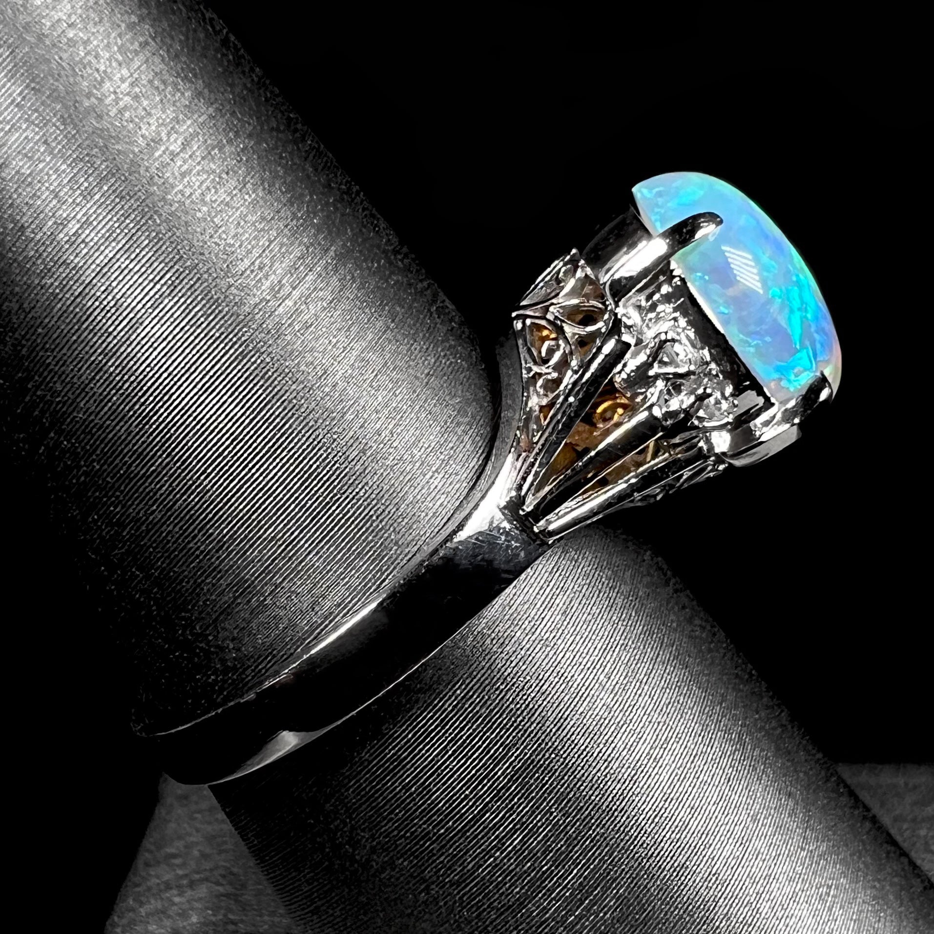 A platinum filigree ring set with a Lightning Ridge crystal opal and diamond accents.