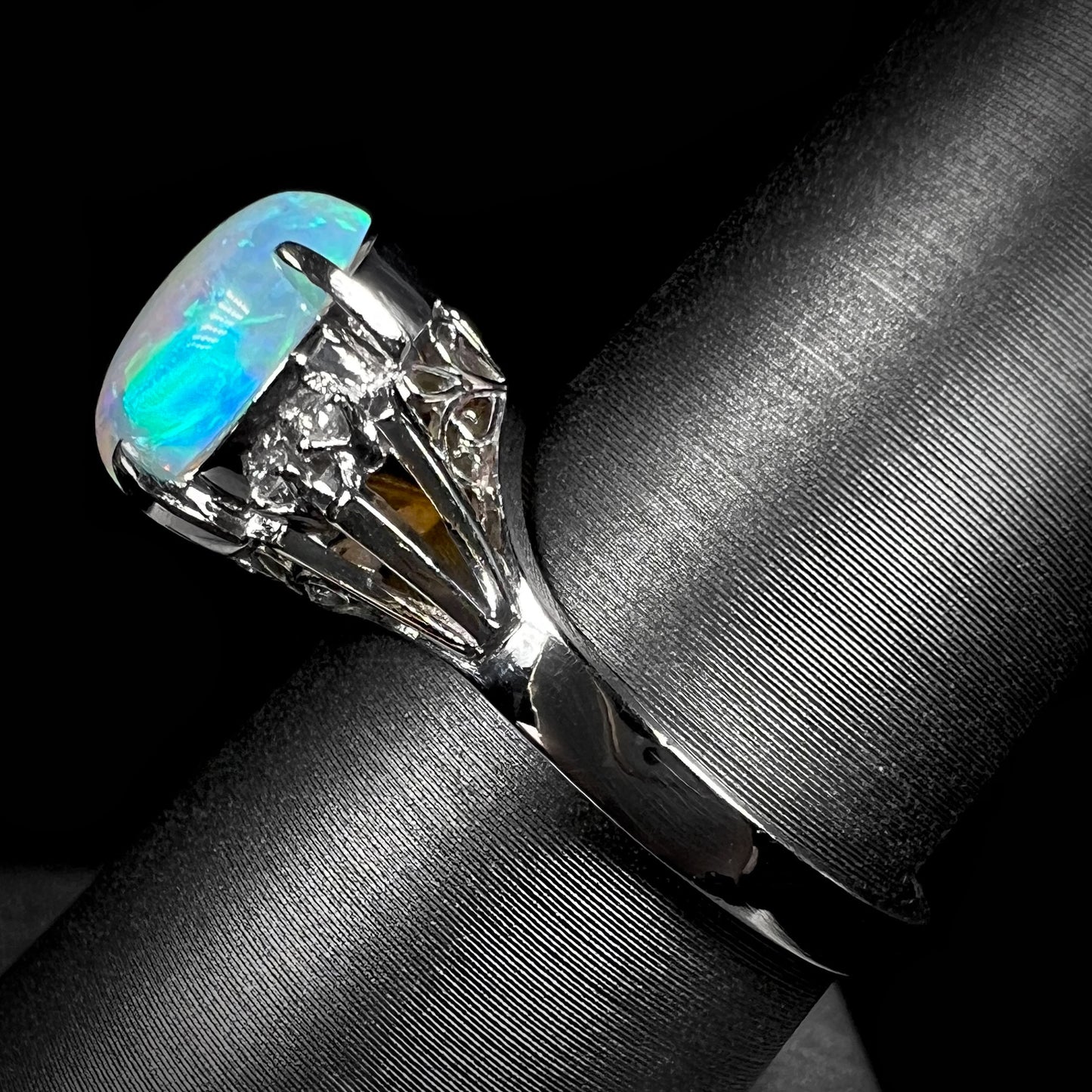 A platinum filigree ring set with a Lightning Ridge crystal opal and diamond accents.