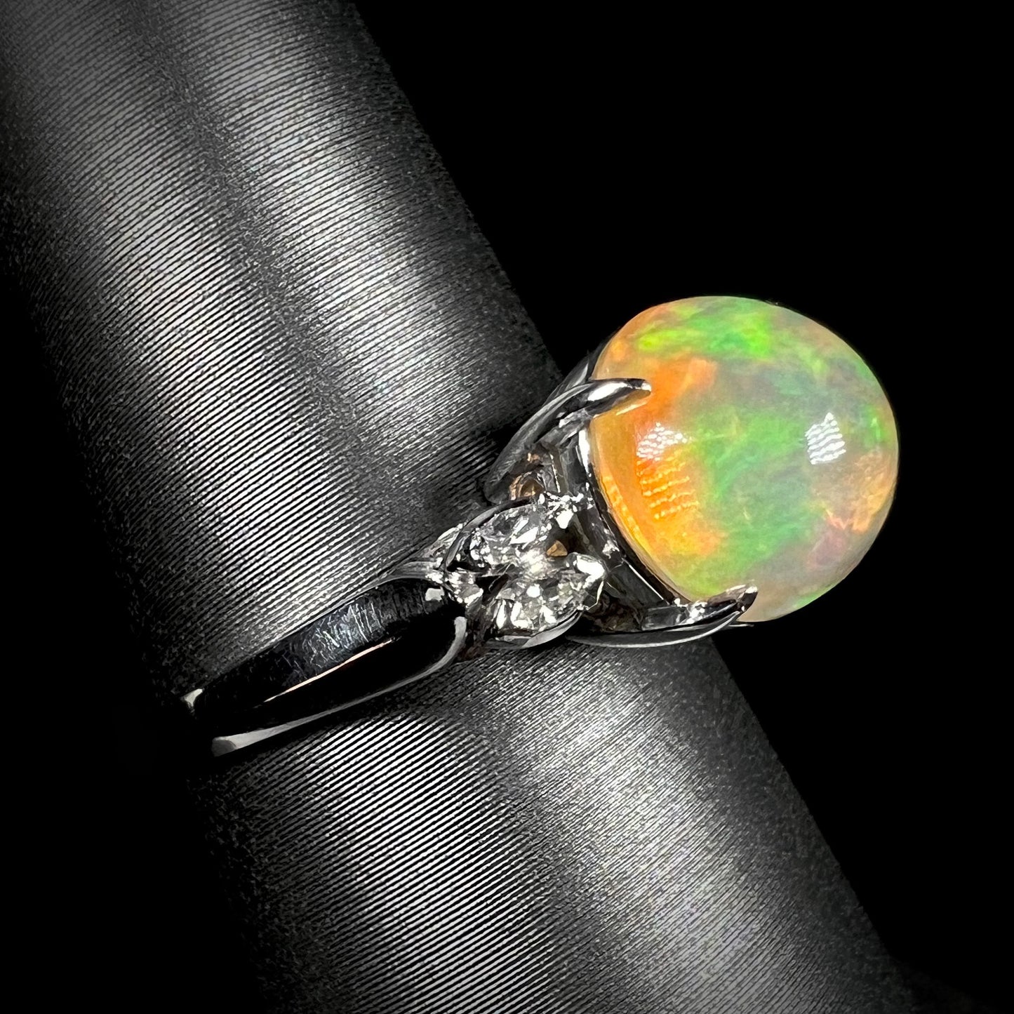 Angled view of a platinum fire opal engagement ring, featuring a 2.28ct Mexican fire opal with green and red fire, accented by marquise-cut diamonds.