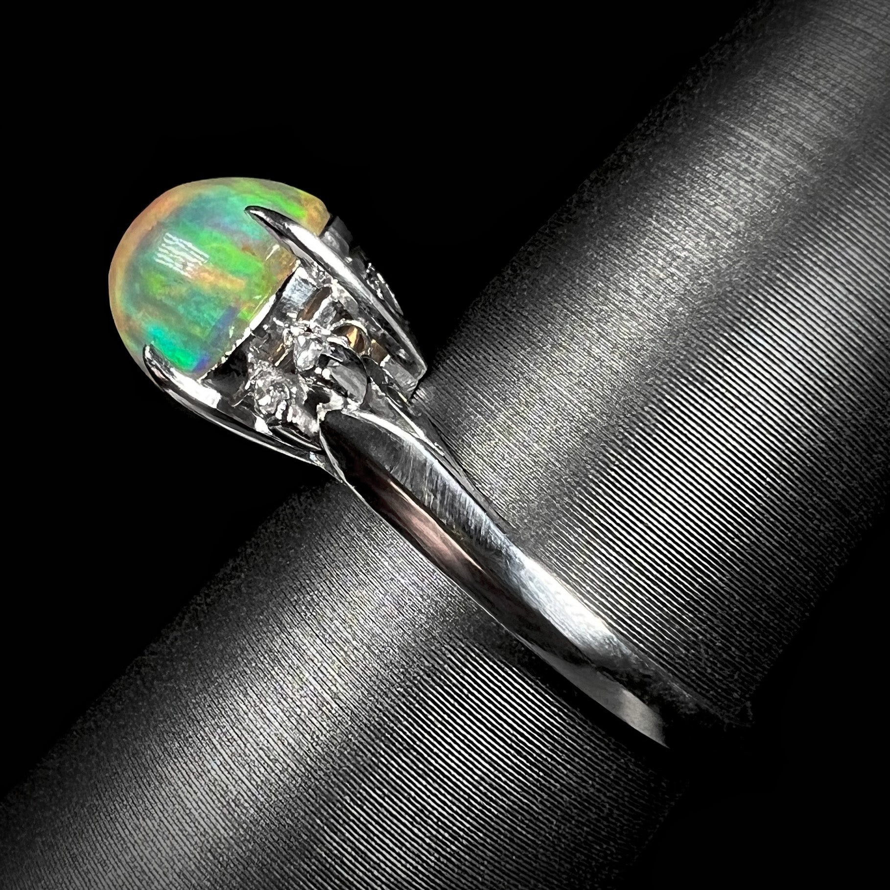 Side view of a platinum fire opal engagement ring, showcasing its elegant band, filigree details, and a 2.28ct Mexican fire opal center stone.