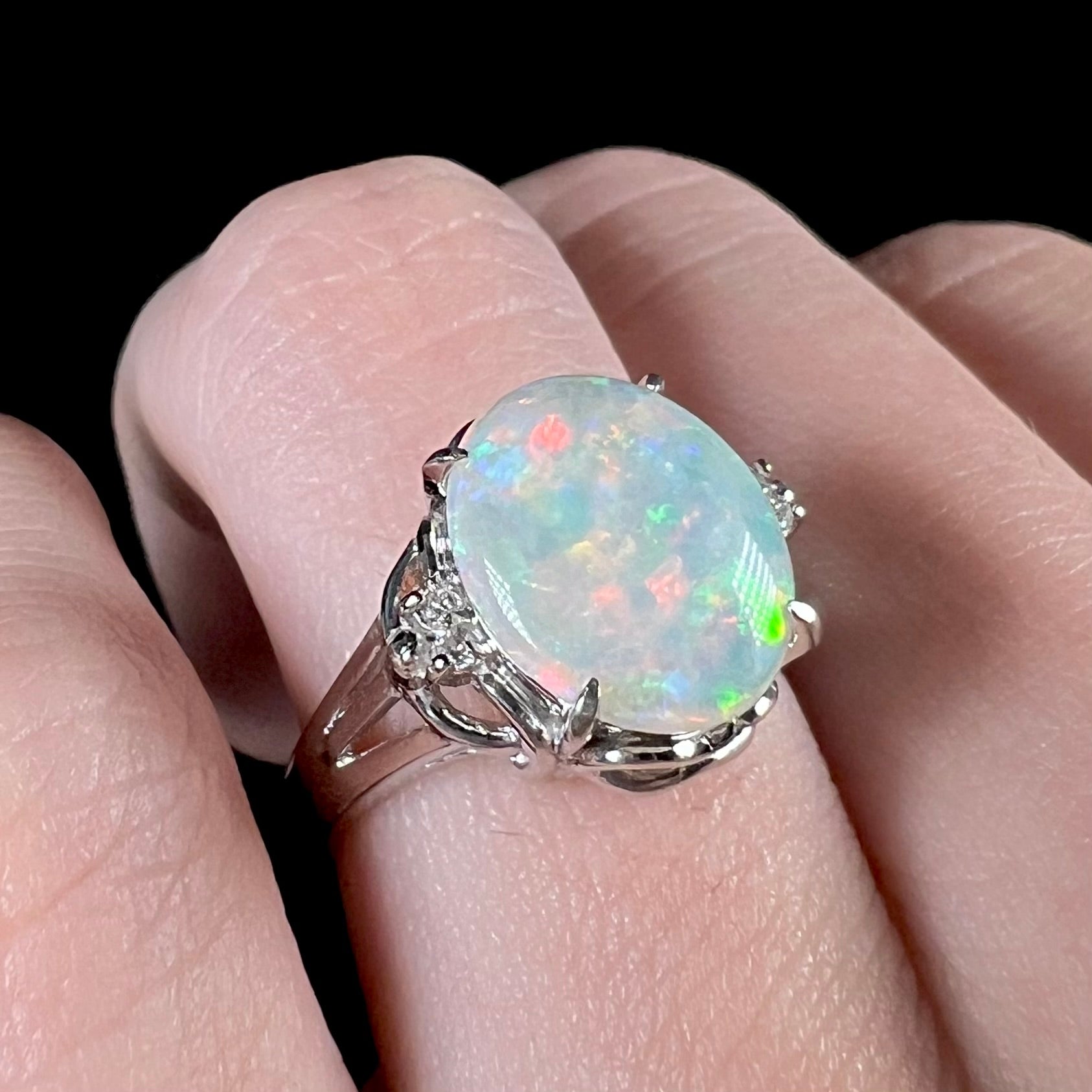 A platinum Coober Pedy opal and diamond ring worn on a finger. 