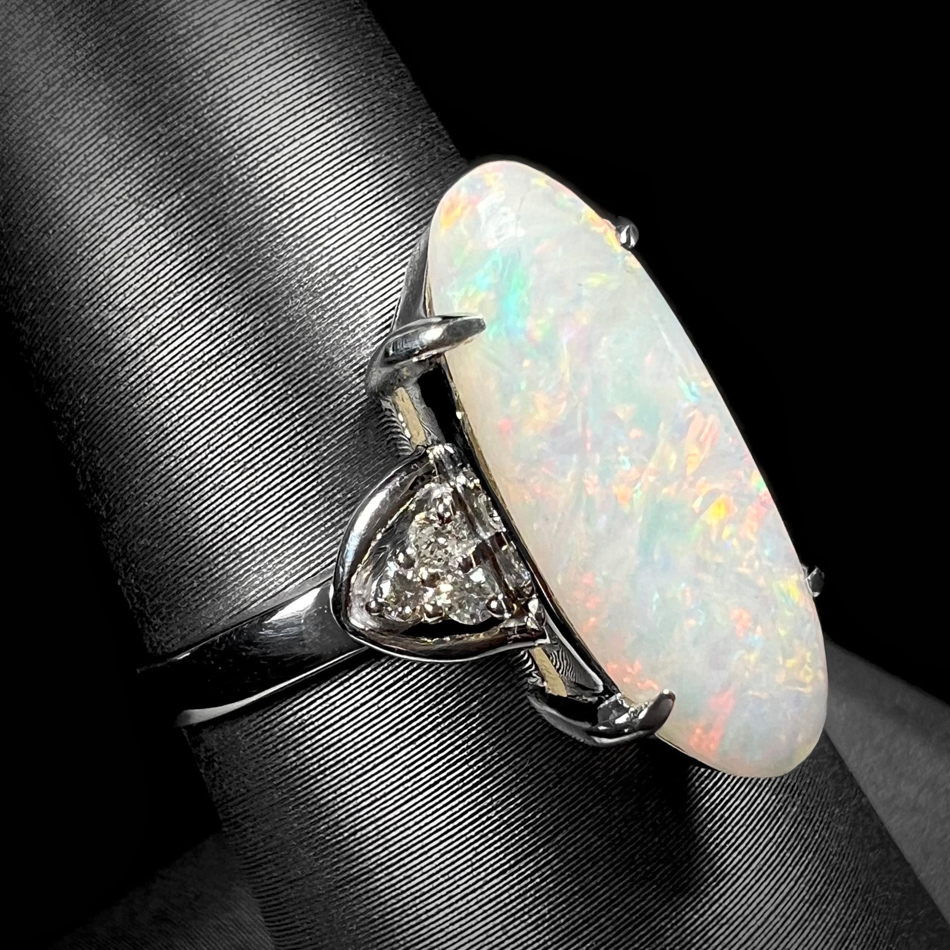 A Coober Pedy white opal platinum ring set with diamond accents.  The opal plays soft pink colors.