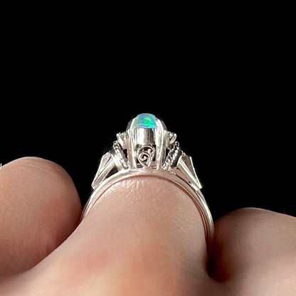 The gallery view of a platinum opal filigree ring, worn on a finger.