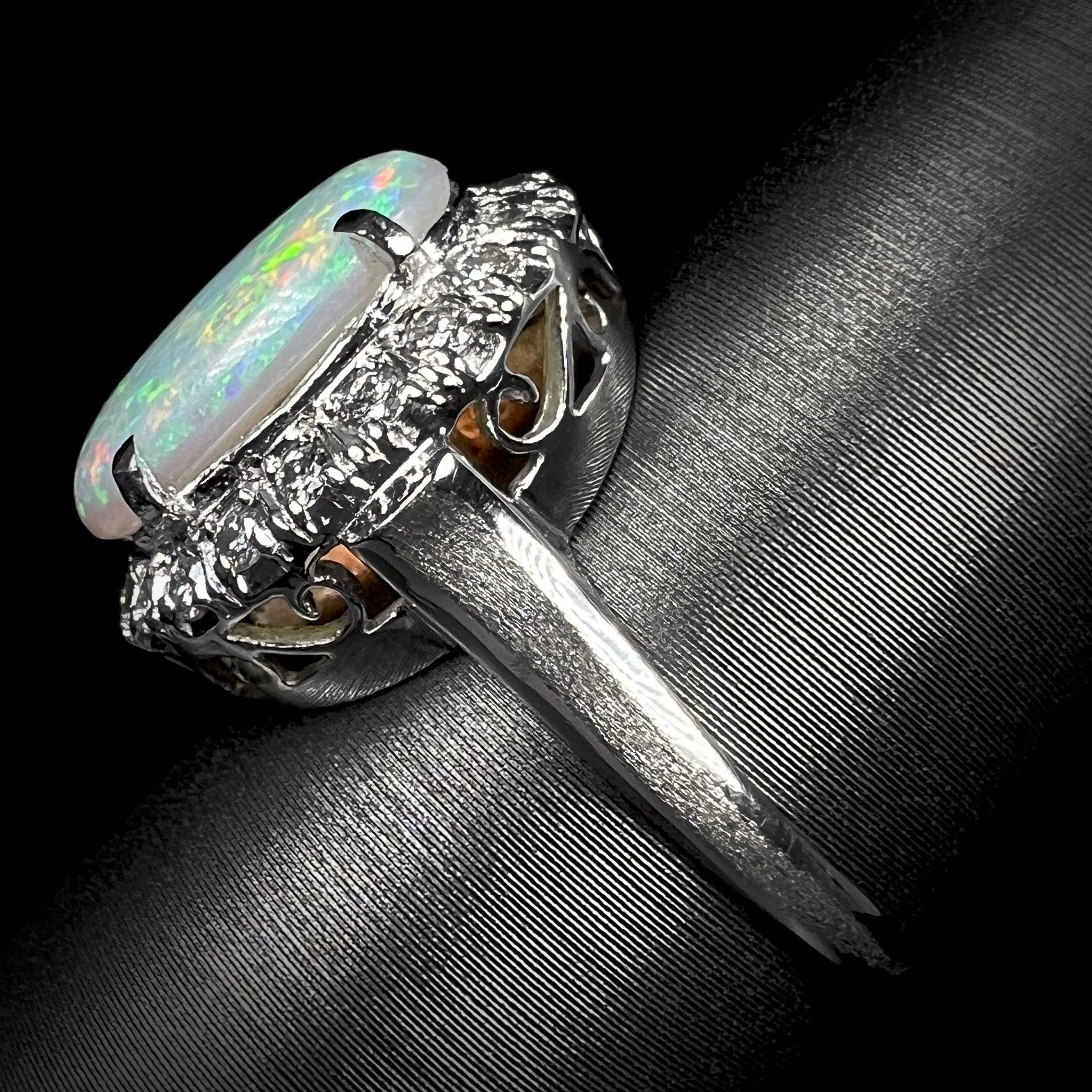 The side angle of a vintage opal and diamond halo ring.  The platinum on the sides of the shank is textured.