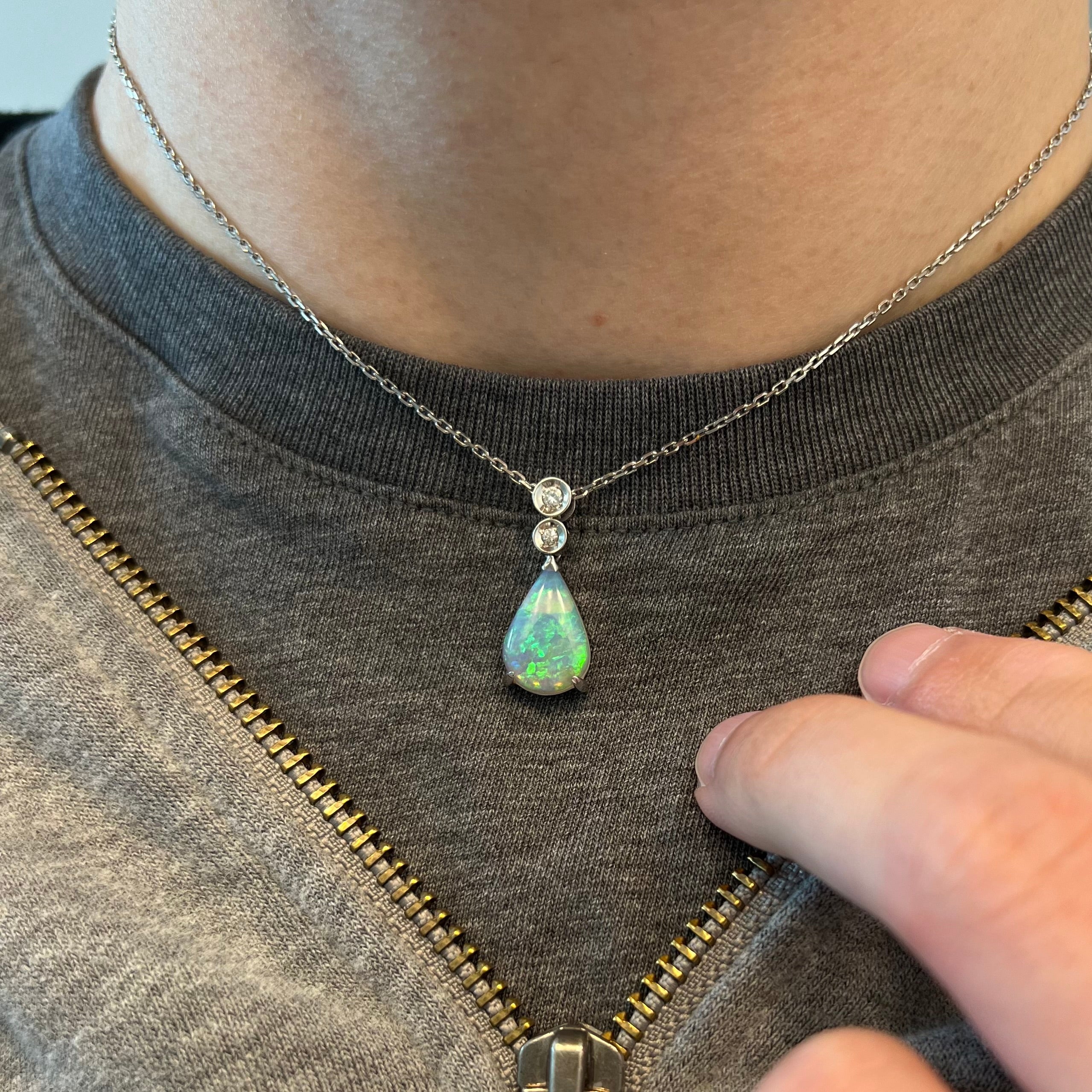 A neck adorned with a pear shaped crystal opal and diamond necklace.