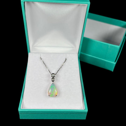 A platinum drop pendant mounted with two diamond accents and a pear shaped green-blue crystal opal.