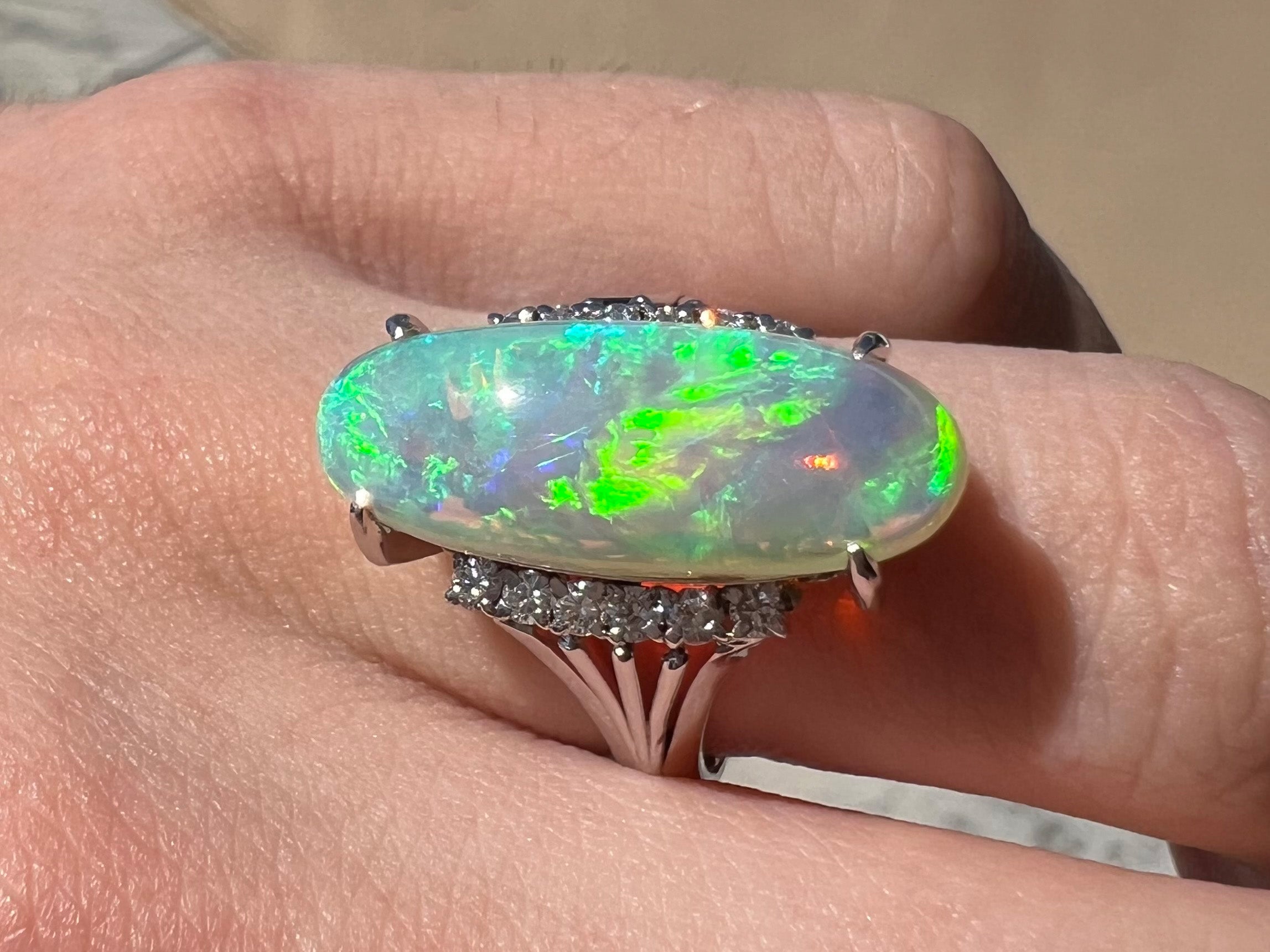 An Australian crystal opal with green fire mounted with diamonds in a platinum filigree ring.