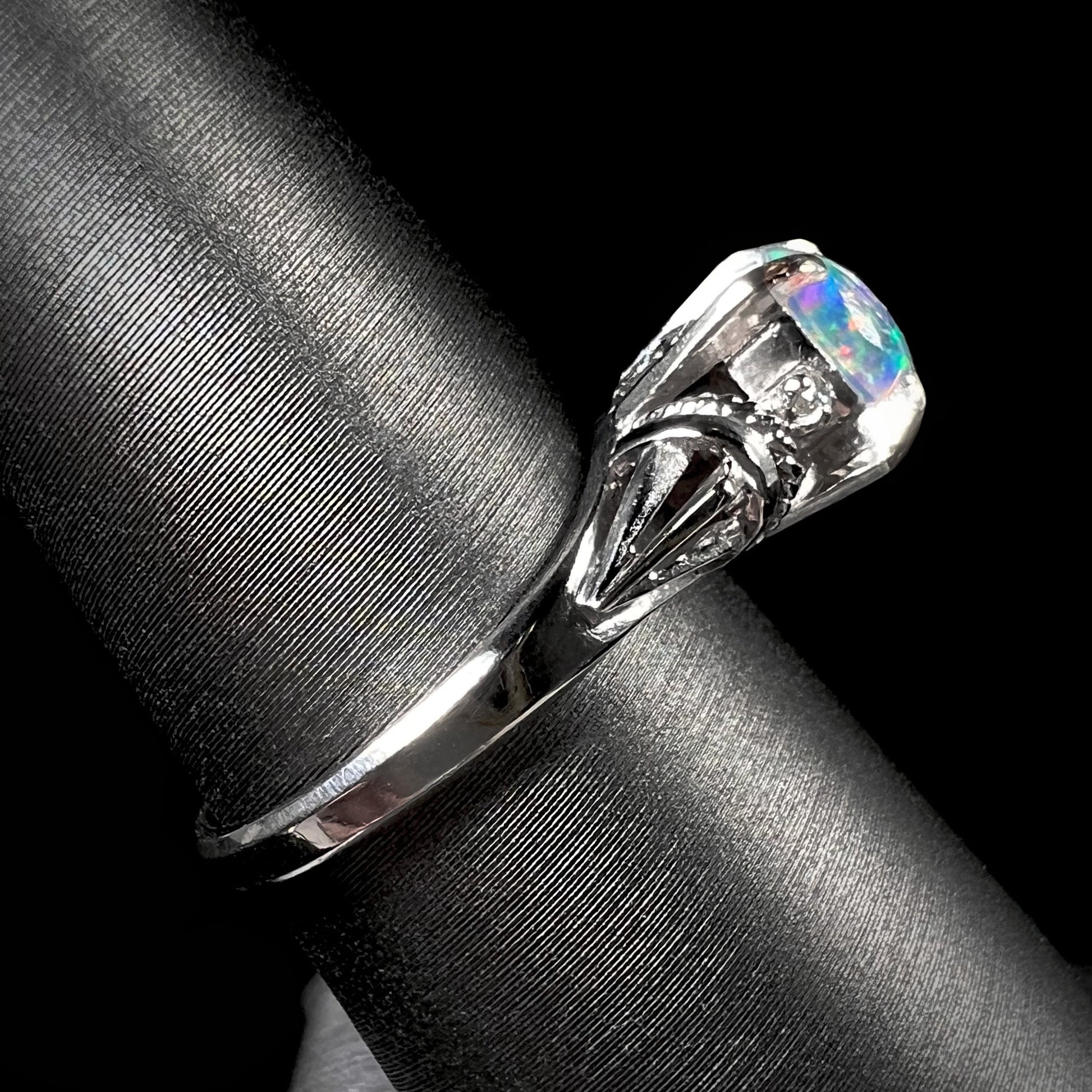 The side angle of a diamond-accented platinum opal ring with rope designs and filigree.