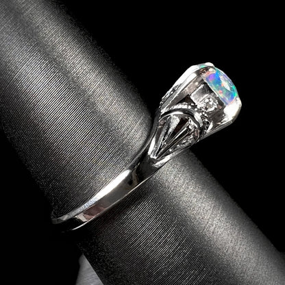 The side angle of a diamond-accented platinum opal ring with rope designs and filigree.