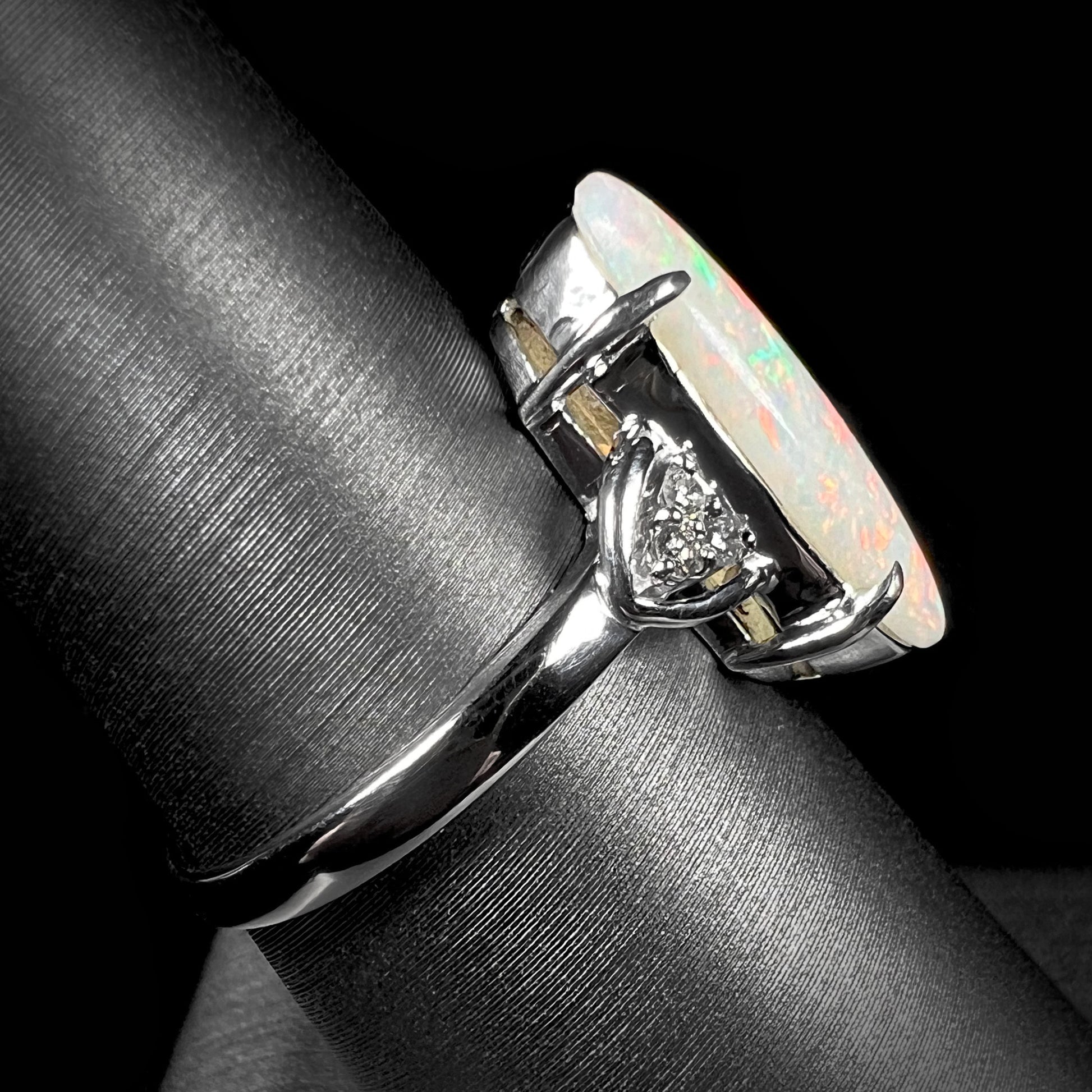 A Coober Pedy white opal platinum ring set with diamond accents.  The opal plays soft pink colors.