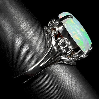 The side view of a platinum opal statement ring.  Filigree design and diamond accents are seen.