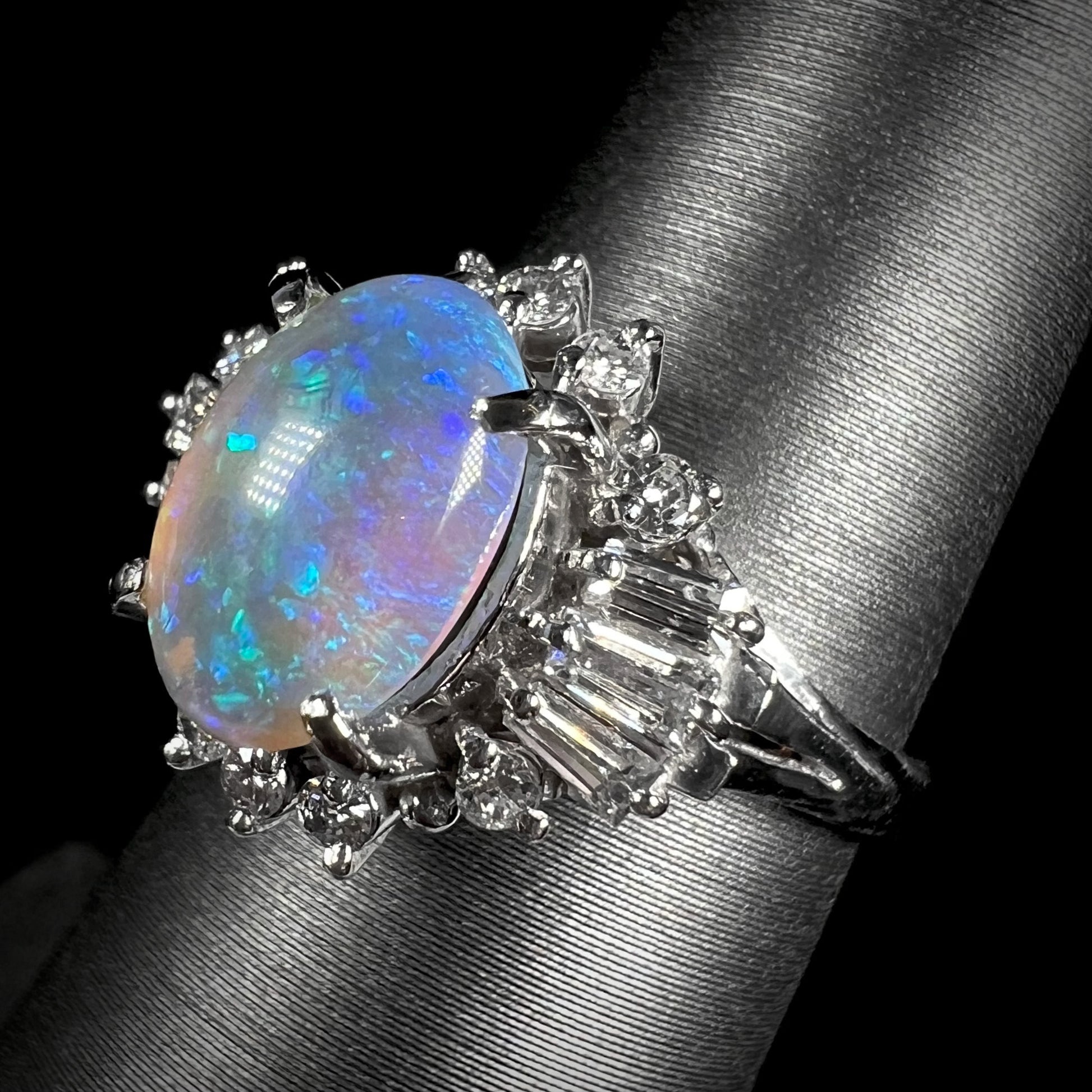 Rotated view of platinum semi-crystal opal engagement ring showing opal with soft purple color play after light source change.