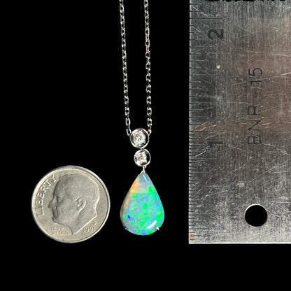 A platinum drop pendant mounted with two diamond accents and a pear shaped green-blue crystal opal.