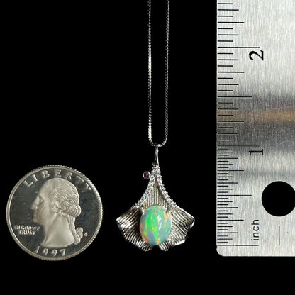 1 inch-long sterling silver ginko leaf pendant set with Ethiopian opal, shown between US quarter coin and ruler