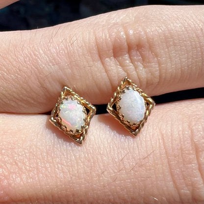 A pair of opal stud earrings.  The opals are set in yellow gold diamond shaped mountings.