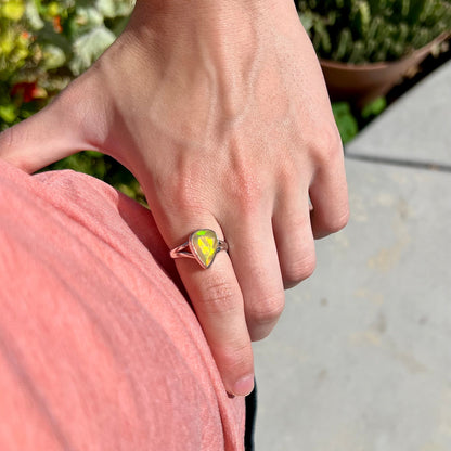 A unisex sterling silver ring set with a faceted pear shaped Ethiopian fire opal.  The opal plays orange, red, and green colors.