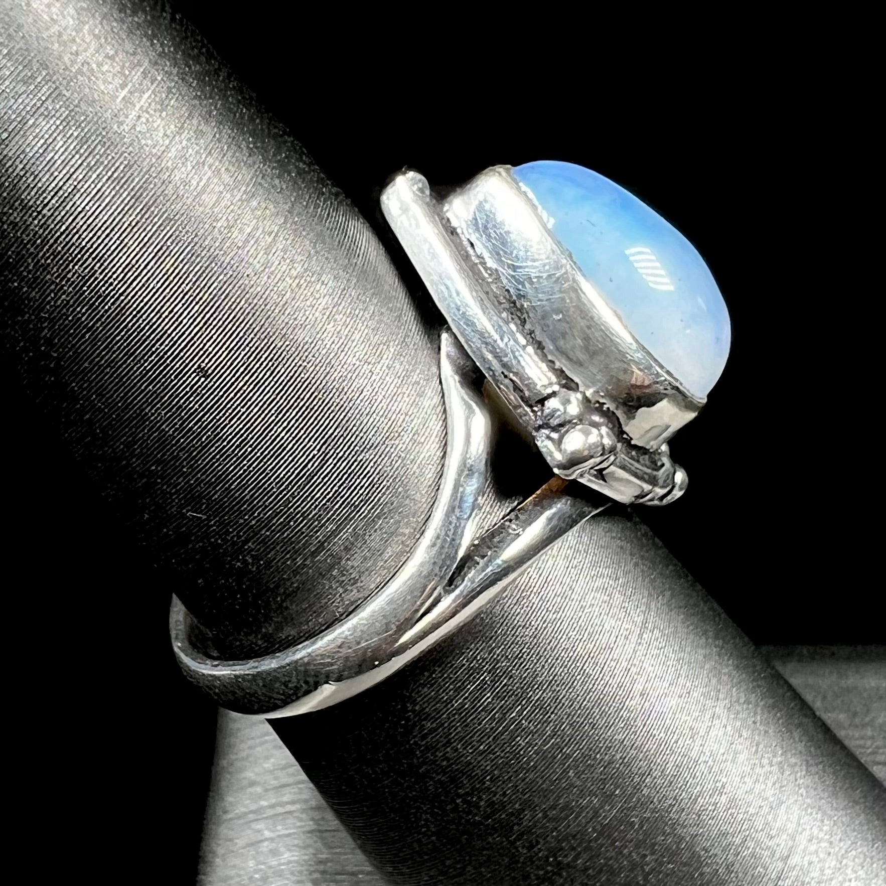 A handmade white metal ring set with a pear shaped opalite cabochon.