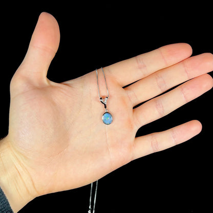 A sterling silver necklace set with a natural black opal doublet and white zircon accent stones.
