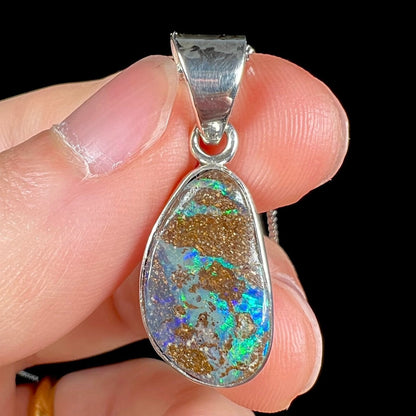 A sterling silver pendant set with an Australian boulder opal on a silver box chain.