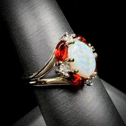 A ladies natural opal ring in yellow gold.  The opal is surrounded by red marquise cut garnets and diamonds.
