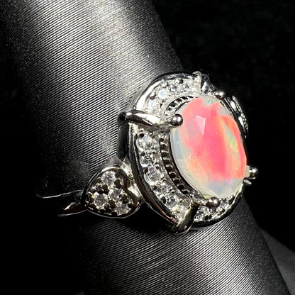 Macro view of silver Ethiopian opal ring with red flash and CZ heart design on display