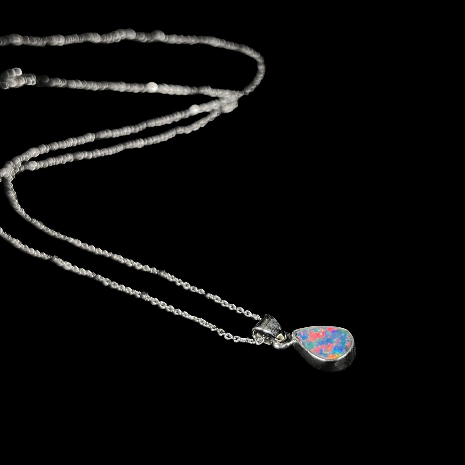 A pear shaped black opal necklace set in sterling silver.  The opal vividly flashes every color of the rainbow.