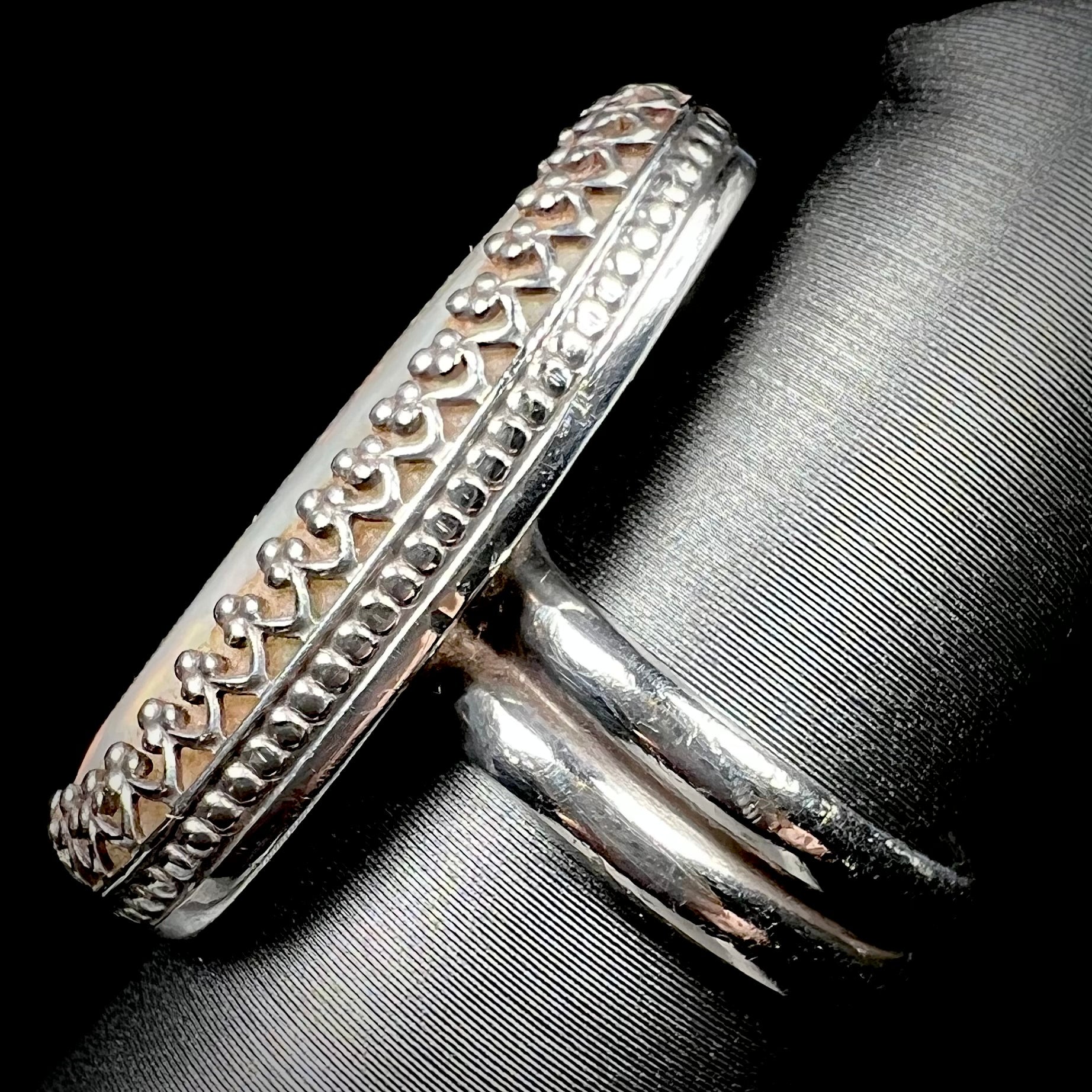 A regal sterling silver opal solitaire ring with a crown design shown close-up from the side view on a ring display.