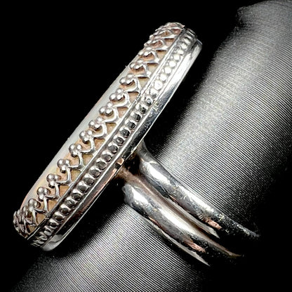 A regal sterling silver opal solitaire ring with a crown design shown close-up from the side view on a ring display.