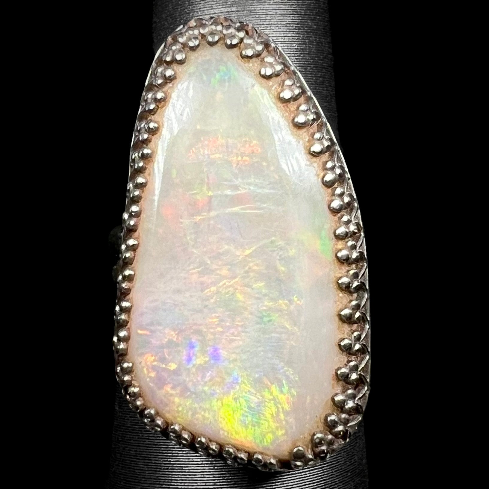 Close-up of a sterling silver Australian opal solitaire cocktail ring with a regal aesthetic, shown on a ring display from the front.
