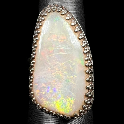 Close-up of a sterling silver Australian opal solitaire cocktail ring with a regal aesthetic, shown on a ring display from the front.
