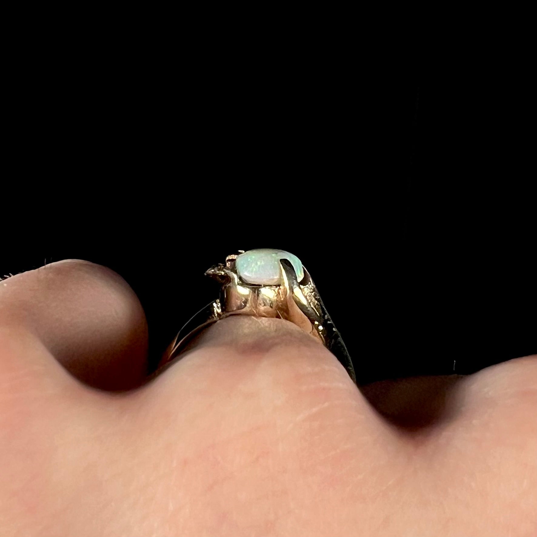 The gallery view of a retro gold opal ring with a leaf design, worn on a hand.