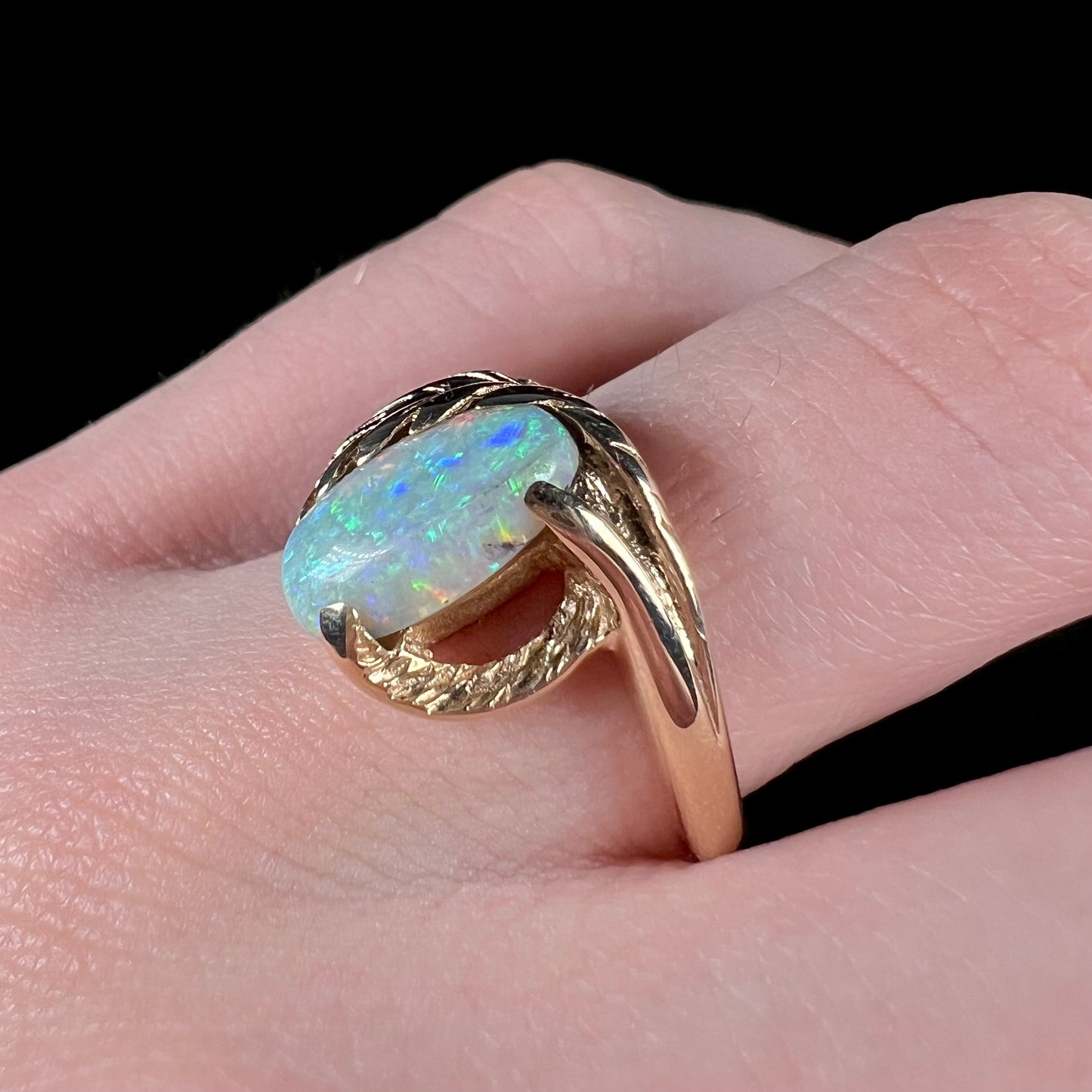 A retro opal ring set in a yellow gold vine-design ring.