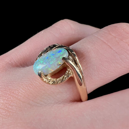 A retro opal ring set in a yellow gold vine-design ring.