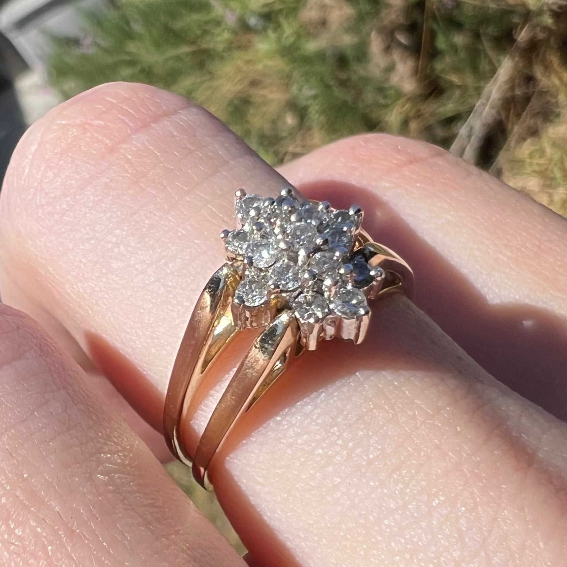 14k gold reversible diamond cluster flip ring, worn on finger and shown close-up in sunlight