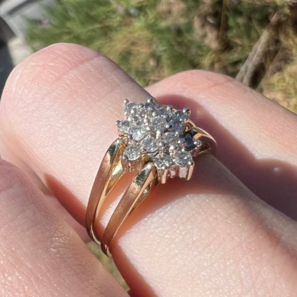 14k gold reversible diamond cluster flip ring, worn on finger and shown close-up in sunlight