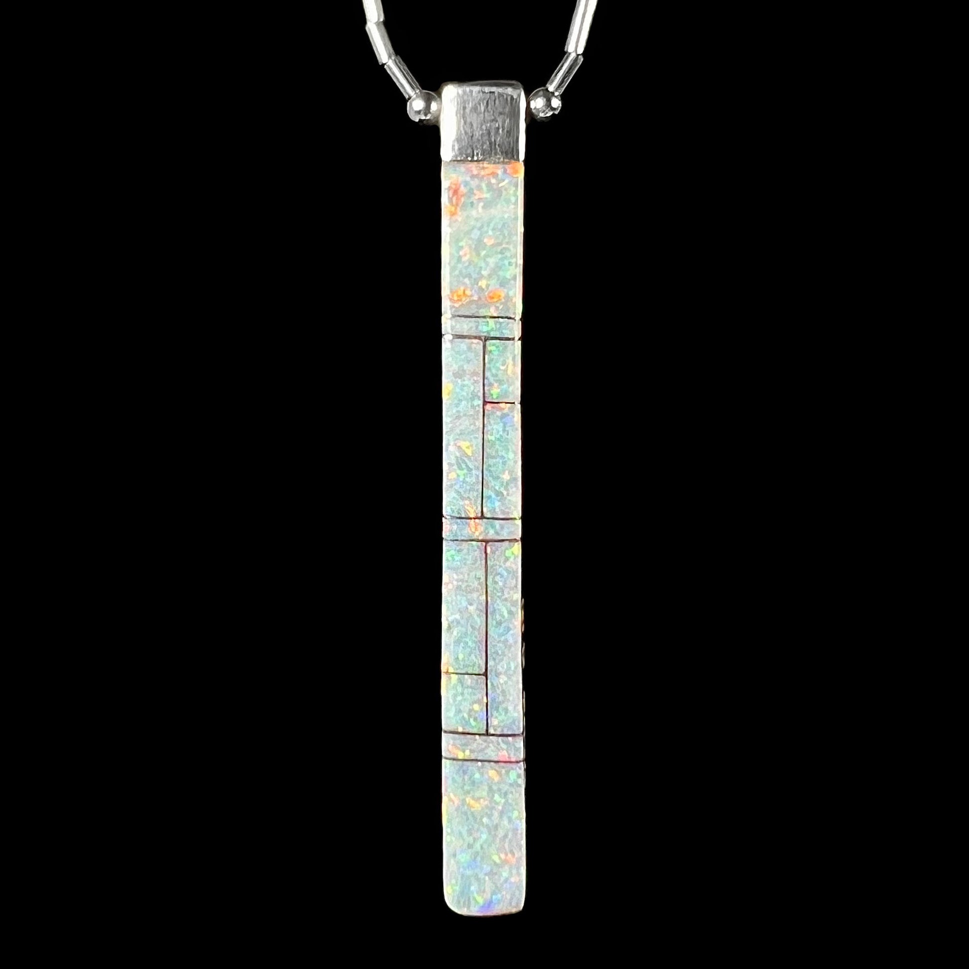 A reversible Navajo inlay pendant by Sheryl Martinez, showing the opal side with white lab-created opal, against a black background.