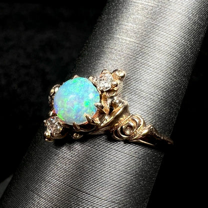 Angled close-up of rose design on shoulder of Art Nouveau 10k gold opal and Old European Cut diamond ring, shown on ring display