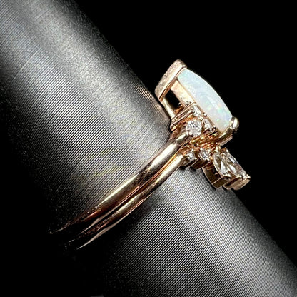 Side view of rose gold opal and moissanite engagement ring set on display, focused on rings' shanks