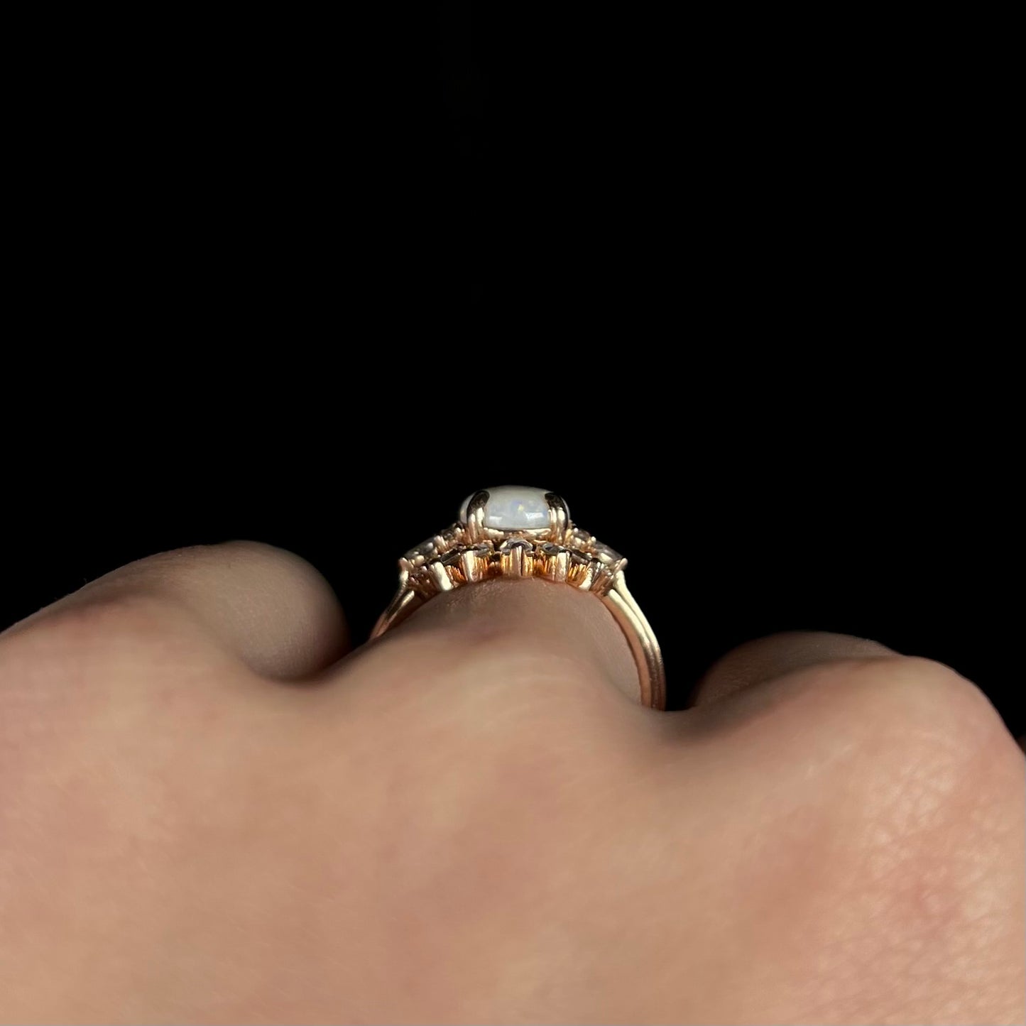 Side gallery profile view of 14k rose gold opal wedding ring set, worn on a hand