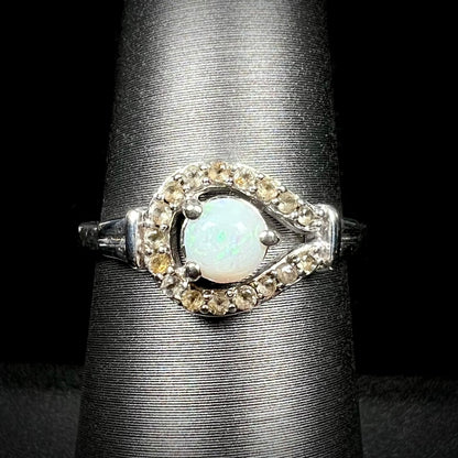 Close-up front view of round Australian white opal women's ring with smoky quartz halo design in sterling silver, shown on ring display